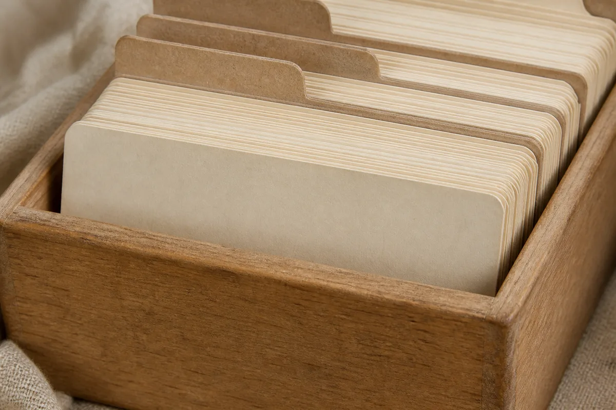 Fiches cartonnées vierges empilées dans une boîte en bois ancienne, texture du carton visible