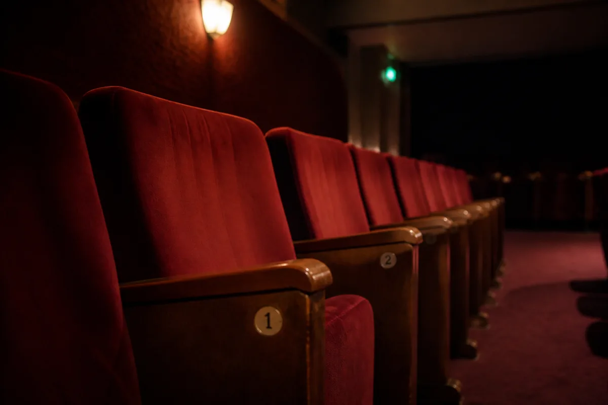 Rangée de fauteuils rouges vides dans une salle de cinéma de quartier