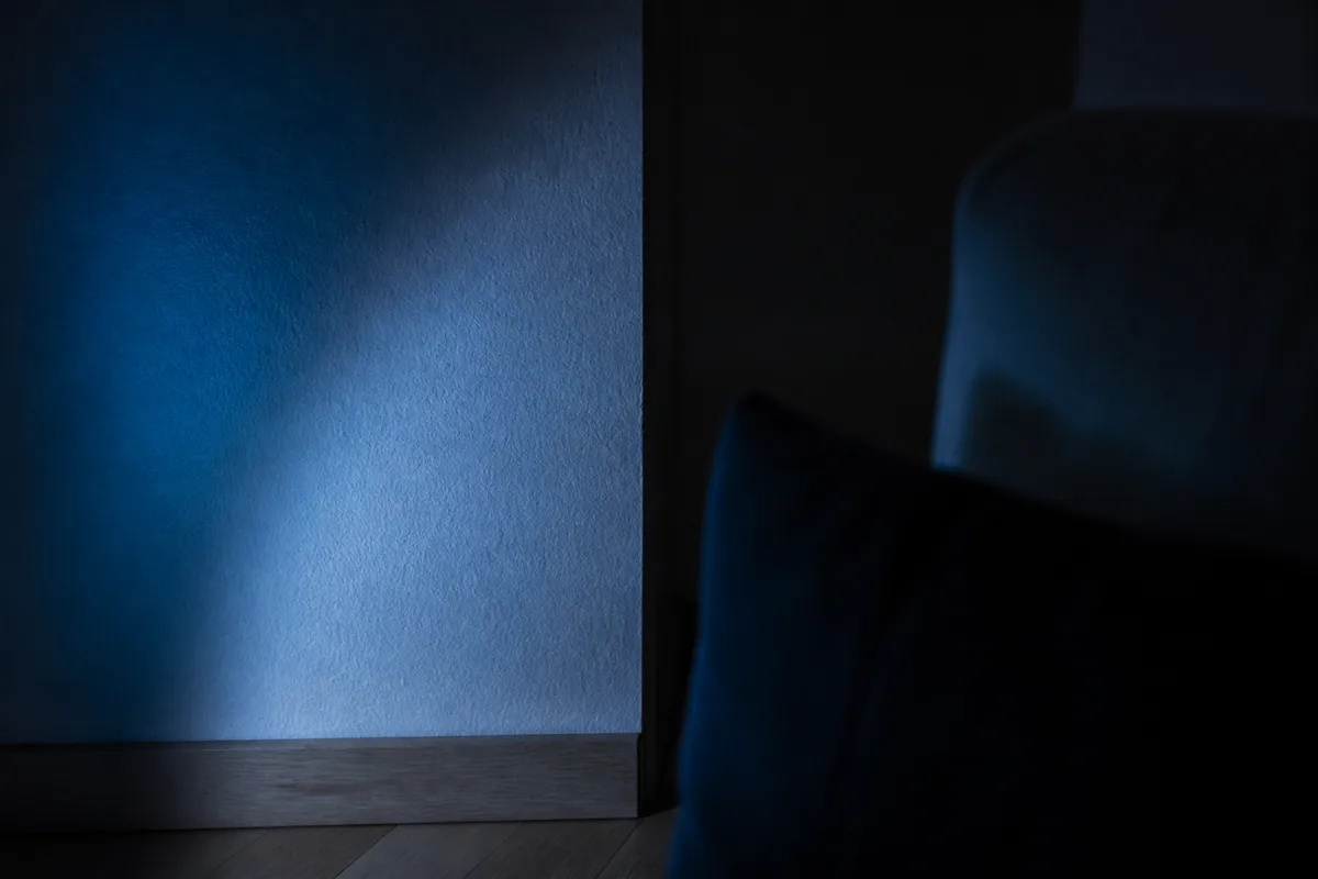 Lumière bleutée d’une soirée projetée sur un mur de salon